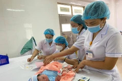 Nhân viên y tế thực hiện sàng lọc các bệnh ở trẻ sau sinh. (Ảnh: PV/Vietnam+)