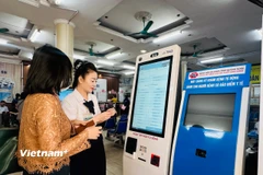 Người dân đăng ký khám bệnh tại các quầy đăng ký khám tự động. (Ảnh: T.G/Vietnam+)