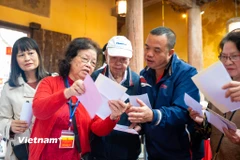 Các cử tri đến bỏ phiếu được thành viên tổ bầu cử hướng dẫn tận tình. (Ảnh: Minh Sơn/Vietnam+)