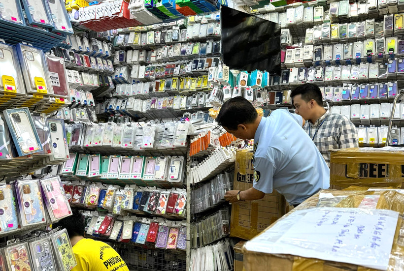 Lực lượng chức năng kiểm tra hộ kinh doanh phụ kiện điện thoại di động. (Ảnh: PV/Vietnam+)