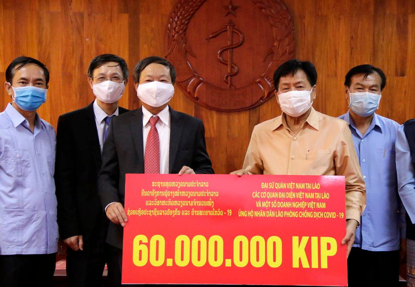 Ông Bounkong Syhavong (phải), Bộ trưởng Bộ Y tế, Phó Trưởng Ban chỉ đạo quốc gia về phòng chống dịch Covid -19 Lào tiếp nhận ủng hộ. (Ảnh: Phạm Kiên/TTXVN)