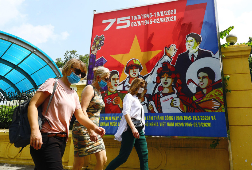 Du khách quốc tế đeo khẩu trang, dạo bộ trên phố Điện Biên Phủ. (Ảnh: Lâm Khánh/TTXVN)