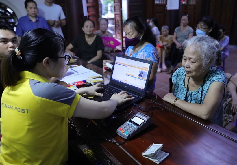 Kiểm tra thông tin của người đến nhận chi trả bảo hiểm, trợ cấp. (Ảnh: Hoàng Hiếu/TTXVN)