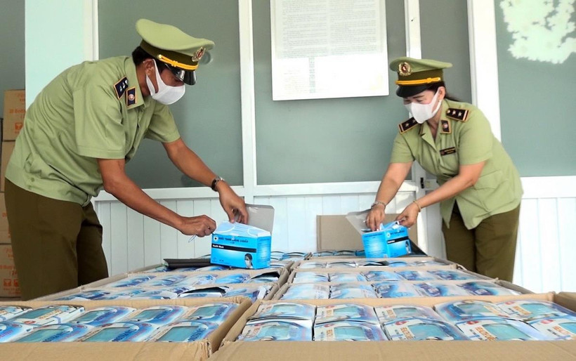 Lực lượng quản lý thị trường kiểm tra số khẩu trang y tế xuất lậu bị bắt giữ. (Ảnh: Công Mạo/TTXVN)
