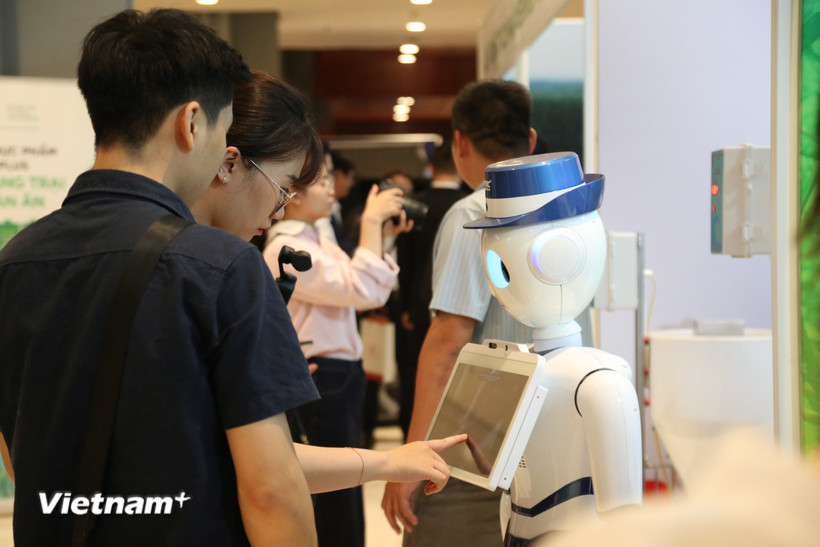 Khách tham quan trải nghiệm thiết bị ứng dụng công nghệ tại khu vực triển lãm. (Ảnh: Phương Nguyễn/Vietnam+)