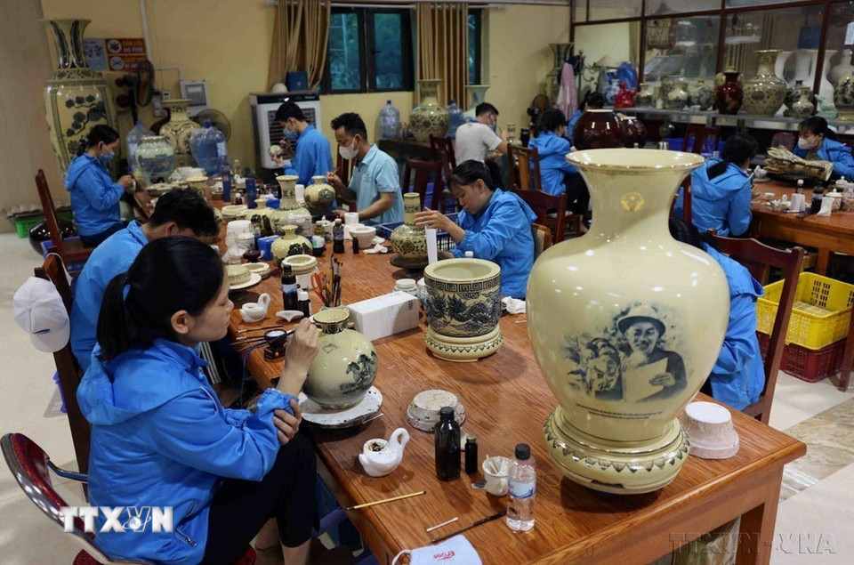 Nghệ nhân dùng bút vẽ những hoa văn hoặc bức tranh nghệ thuật lên sản phẩm gốm của Công ty Cổ phần Gốm Chu Đậu (thôn Chu Đậu, xã Thái Tân, huyện Nam Sách, tỉnh Hải Dương). (Ảnh: Vũ Sinh/TTXVN)