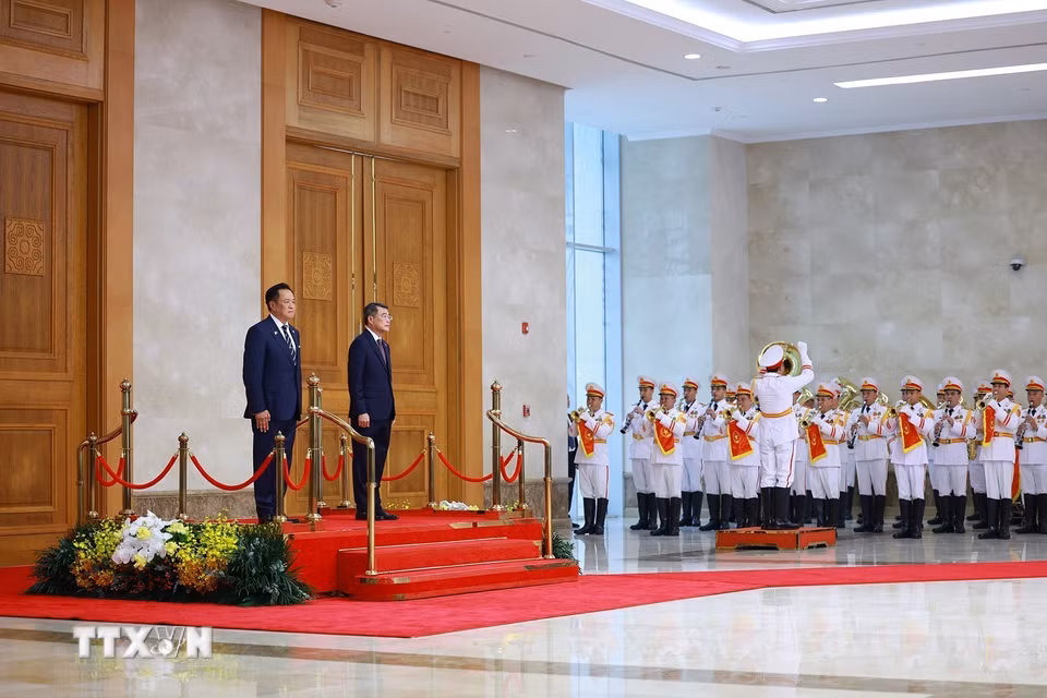 Thủ tướng Lê Minh Hưng và Thủ tướng Vương quốc Thái Lan Anutin Charnvirakul nghe quân nhạc cử Quốc thiều hai. nước. (Ảnh: Dương Giang/TTXVN)