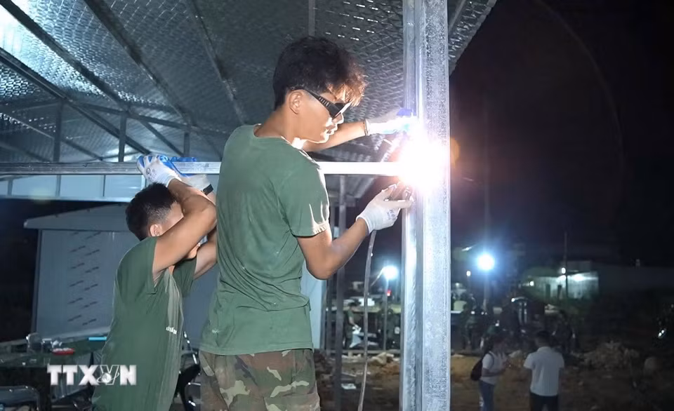 Cán bộ chiến sỹ làm xuyên ngày đêm với mục tiêu chung sớm dựng xong những căn nhà cho người dân vùng lũ Mường Than. (Ảnh: Quý Trung/TTXVN)