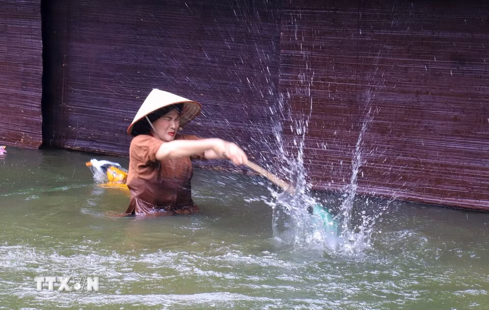 Nghệ nhân ngâm mình nhiều giờ trong nước, dồn hết tâm sức để truyền cảm xúc vào những con rối gỗ khô cứng. (Ảnh: Phương Anh/TTXVN phát)