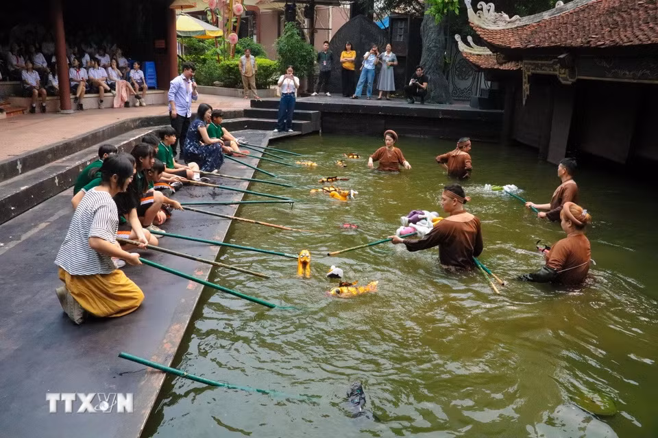 Cô giáo và các học sinh Trung Quốc thích thú trải nghiệm múa rối nước dân gian Việt Nam. (Ảnh: Phương Anh/TTXVN phát)