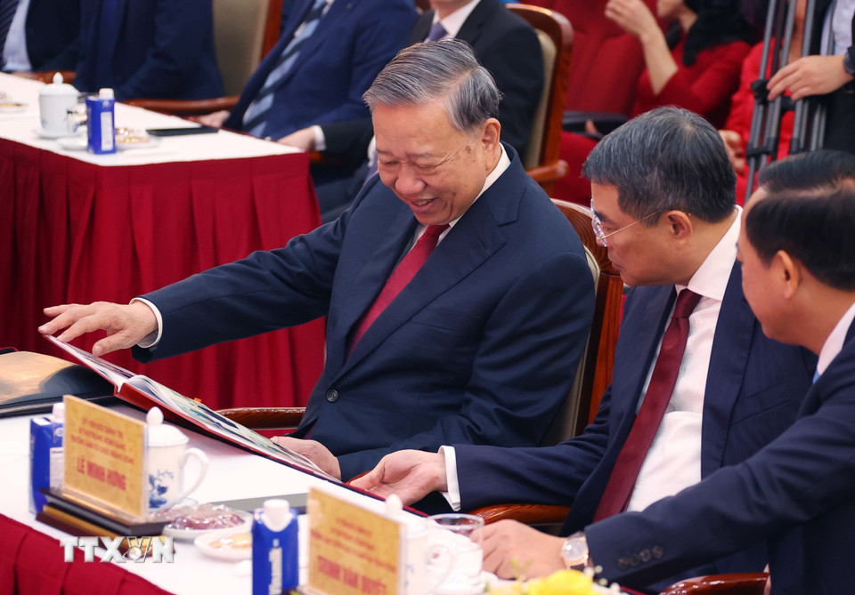 Tổng Bí thư Tô Lâm xem cuốn sách ảnh do phóng viên Ban biên tập Ảnh thực hiện. (Ảnh: Văn Điệp/TTXVN)