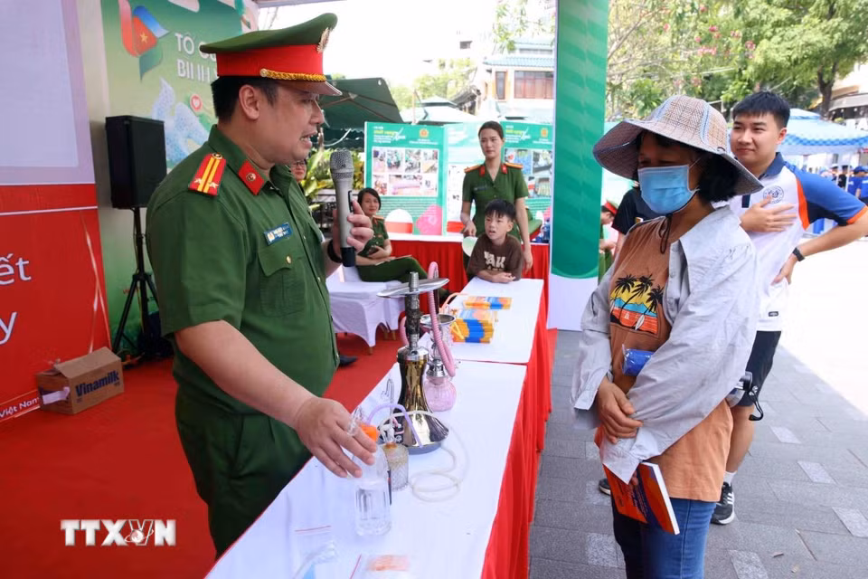 Người dân được các chiến sỹ Công an Thủ đô tuyên truyền về tác hại và cách phòng, chống ma túy tại buổi lễ. (Ảnh: Phạm Kiên/TTXVN)