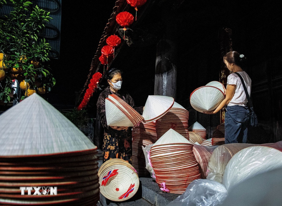 Tại các phiên chợ, người dân trong làng mang những chồng nón ra sân đình để bày bán. (Ảnh: Vân Chi/TTXVN phát)