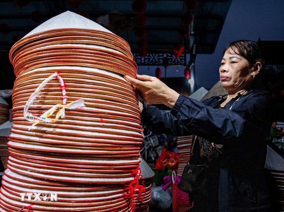 Kết thúc phiên chợ, những người mua buôn tập trung kiểm đếm, tổng hợp số lượng nón đã thu mua. (Ảnh: Vân Chi/TTXVN phát)