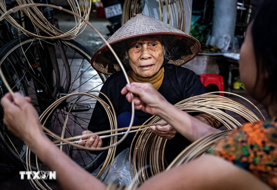 Người mua tỉ mỉ lựa từng vòng nón làm bằng cật tre, ưu tiên những chiếc nứa vót nhỏ, đều tay; khi nối phải tròn trịa, liền mạch, không chắp vá hay gợn lỗi. (Ảnh: Vân Chi/TTXVN phát)