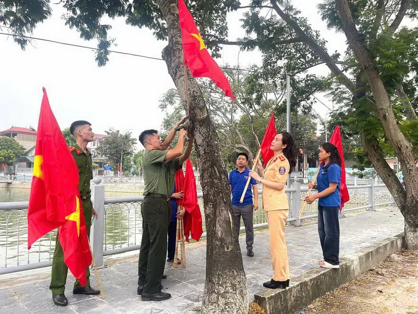 Đoàn viên thanh niên treo cờ Tổ quốc và cờ Đảng xung quanh hồ Mai Trai, xã Vạn Thắng, huyện Ba Vì. (Ảnh: Mạnh Khánh/TTXVN)