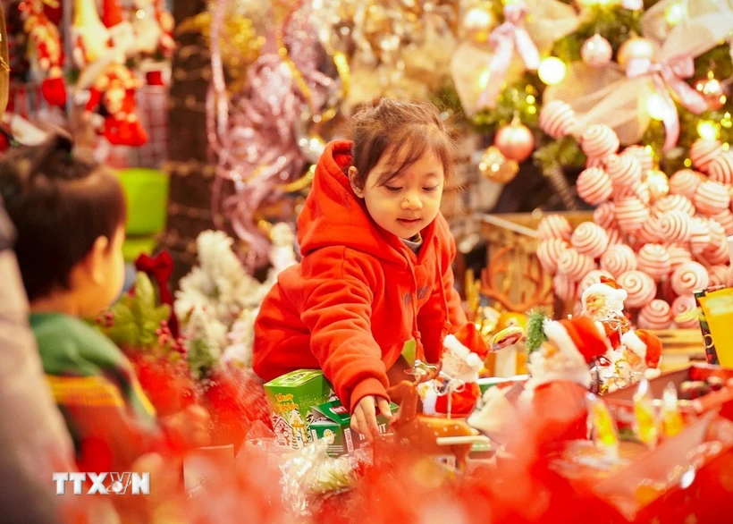 Một bé gái lựa chọn cho mình món đồ chơi Giáng sinh trên phố Hàng Mã, Hà Nội. (Ảnh: Khánh Hòa/TTXVN)