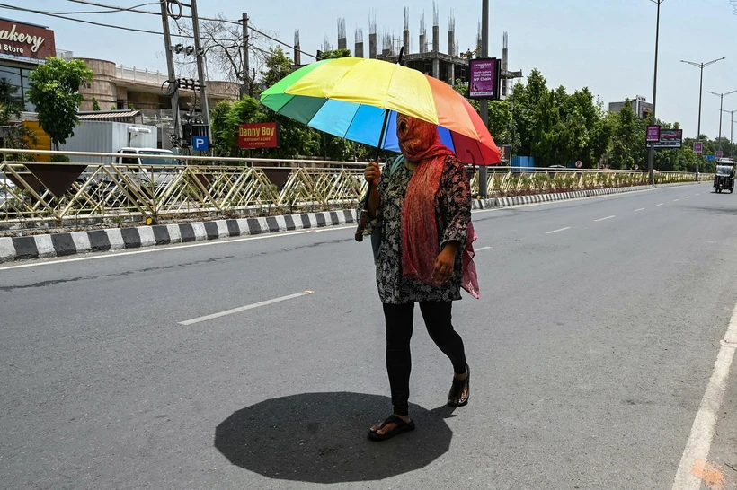 Người dân che ô khi di chuyển ngoài trời trong ngày nắng nóng tại Amritsar, Ấn Độ ngày 4/6/2024. (Ảnh: AFP/TTXVN)