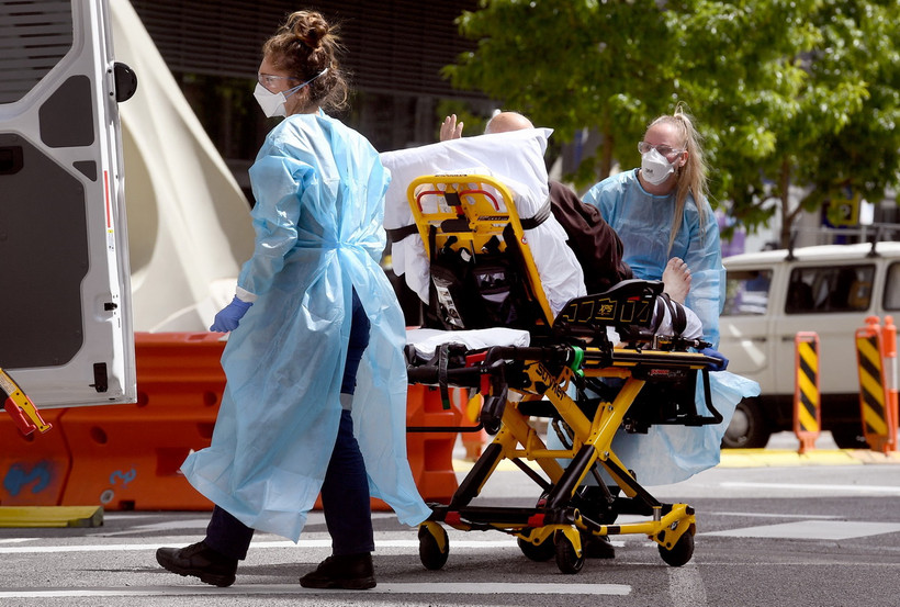 Nhân viên y tế chuyển bệnh nhân nhiễm COVID-19 tới bệnh viện ở Melbourne, Australia. (Ảnh: AFP/TTXVN)