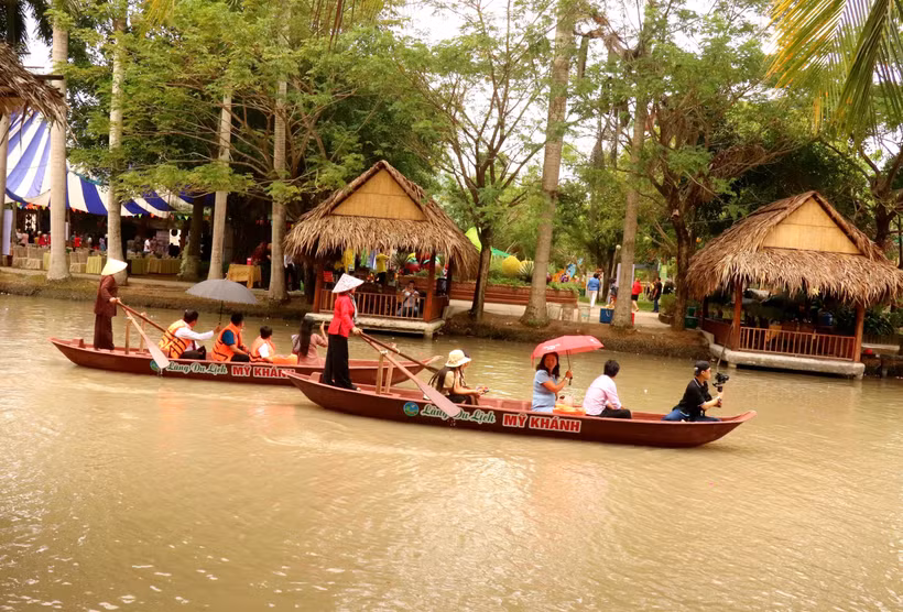 Du khách trải nghiệm chèo thuyền trên sông ở Làng du lịch Mỹ Khánh. (Ảnh: Thu Hiền/TTXVN)
