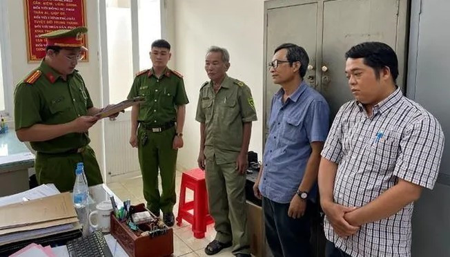 Công an đọc lệnh khởi tố, bắt tạm giam bị can Nguyễn Đức Khuê và Lê Ngọc Muôn. (Ảnh: TTXVN phát)