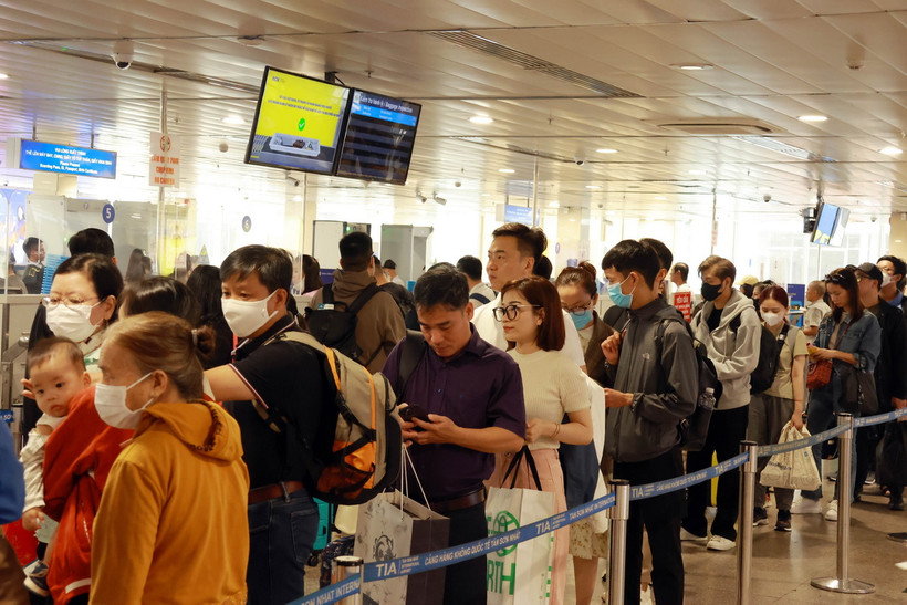 Hành khách xếp hàng làm thủ tục soi chiếu kiểm tra an ninh tại sân bay Tân Sơn Nhất. (Ảnh: Quang Châu/TTXVN)