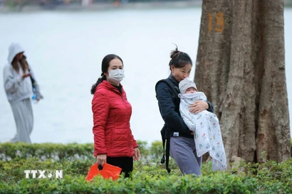 Trẻ nhỏ được che chắn kỹ chống rét khi phải di chuyển ngoài trời. (Ảnh: Hoàng Hiếu/TTXVN)