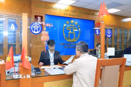 Cán bộ, công chức Trung tâm Phục vụ hành chính công thành phố Hà Nội-Chi nhánh số 3 hướng dẫn người dân hoàn thiện hồ sơ thủ tục hành chính. (Ảnh: TTXVN phát)