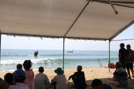 Trên bờ, người thân các nạn nhân luôn hướng về phía biển, nơi các lực lượng chức năng đang tìm kiếm các em. (Ảnh: Đinh Hương/TTXVN)