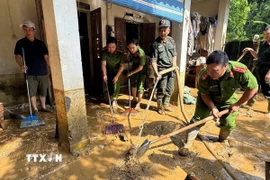 Lực lượng chức năng hỗ trợ người dân khắc phục hậu quả mưa lũ. (Ảnh: TTXVN phát)