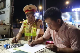 Lực lượng Cảnh sát giao thông trạm Đồng Phú lập biên bản, xử lý xe khách vi phạm giao thông. (Ảnh: Đậu Tất Thành/TTXVN)