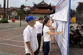 Người dân khu phố Phú Mẫn, thị trấn Chờ, huyện Yên Phong tìm hiểu các đề án sáp nhập. (Ảnh: Thái Hùng/TTXVN)