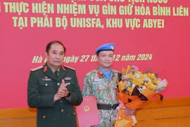Thượng tướng Phùng Sĩ Tấn, Phó Tổng Tham mưu trưởng Quân đội Nhân dân Việt Nam trao quyết định và tặng hoa cho Thiếu tá Hoàng Đình Công trước khi lên đường. (Ảnh: Trọng Đức/TTXVN)