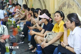 Bên ngoài điểm thi Trung học phổ thông Chu Văn An, nhiều phụ huynh ngồi đợi con. (Ảnh: Lê Đông/TTXVN)