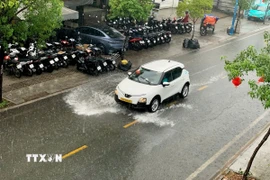 Ôtô lưu thông trong cơn mưa trái mùa chiều 6/1/2026 trên đường Kênh Tân Hóa, phường Tân Phú. (Ảnh: Hồng Đạt/TTXVN)