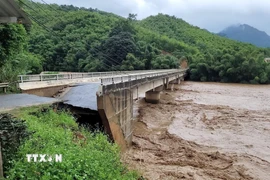 Nước sông Luồng dâng cao chảy xiết làm sập chân, mố cầu Sơn Thủy. (Ảnh: TTXVN phát)