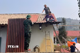 Cán bộ, chiến sỹ Bộ Chỉ huy quân sự tỉnh Lào Cai giúp bà con xã Bắc Hà lợp lại mái nhà, nhanh chóng ổn định cuộc sống sau trận mưa đá. (Ảnh: TTXVN phát)