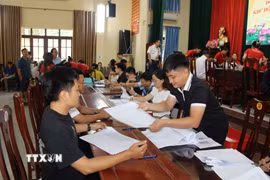 Người dân nhận tiền bồi thường giải phóng mặt bằng Cảng hàng không quốc tế Gia Bình. (Ảnh: Thanh Thương/TTXVN)