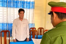 Công an tỉnh An Giang tống đạt các quyết định khởi tố vụ án, khởi tố bị can và lệnh cấm đi khỏi nơi cư trú đối với Đỗ Văn Quý. (Ảnh: TTXVN phát)
