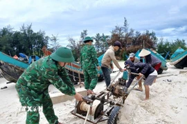 Bộ đội Biên phòng Quảng Trị hỗ trợ ngư dân đưa thuyền neo đậu ở vị trí an toàn, đảm bảo hạn chế thiệt hại do mưa bão gây ra. (Ảnh: TTXVN phát)