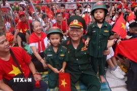 Ông cháu cùng chờ xem buổi tổng hợp luyện diễu binh, diễu hành A80 lần thứ 2. (Ảnh: Văn Điệp/TTXVN)