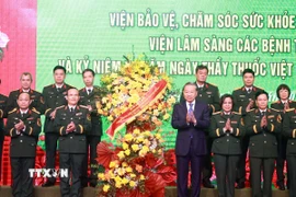 Tổng Bí thư Tô Lâm tặng hoa chúc mừng đội ngũ giáo sư, bác sỹ Bệnh viện Trung ương Quân đội 108. (Ảnh: Thống Nhất/TTXVN)