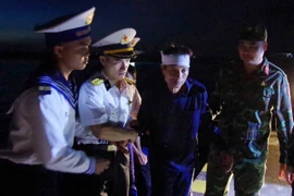 Các chiến sỹ đảo Trường Sa dìu bệnh nhân Tiêu Viết Bút đến Trung tâm y tế. (Ảnh: TTXVN phát)