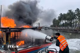 Lực lượng chức năng nỗ lực khống chế tàu cá bị cháy. (Ảnh: TTXVN phát)