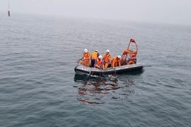 Lực lượng đưa thi thể thuyền viên lên tàu. (Ảnh: TTXVN phát)