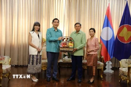 Đại sứ Phạm Việt Hùng (trái) và phu nhân trao lẵng quà tặng Đại sứ Lào Sisavath Inphachanh và phu nhân. (Ảnh: Đỗ Sinh/TTXVN)
