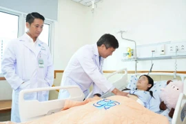 Bác sỹ Bệnh viện Đại học Y dược Thành phố Hồ Chí Minh thăm khám cho bệnh nhân 18 tuổi bị ung thư dạ dày giai đoạn tiến xa. (Ảnh: TTXVN phát)