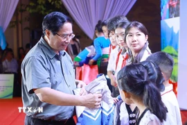 Thủ tướng Phạm Minh Chính tặng áo ấm cho học sinh xã Bát Mọt. (Ảnh: Dương Giang/TTXVN)