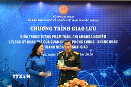 Trung tướng Phạm Tuân tặng chị Amanda Nguyễn cuốn sách kỷ niệm ghi dấu chuyến bay lịch sử của ông. (Ảnh: TTXVN phát)