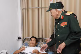 Thiếu tướng Võ Văn Chót, Trưởng ban danh dự Ban Liên lạc quân tình nguyện và chuyên gia quân sự Việt Nam giúp cách mạng Lào tỉnh Nghệ An, trao quà cho thương binh nặng đang điều trị tại Bệnh viện Trung ương Quân đội 103 Lào. (Ảnh: Xuân Tú/TTXVN)